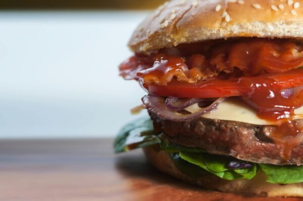 Close-up of a mouthwatering gourmet burger with layers of fresh toppings and oozing sauce.
