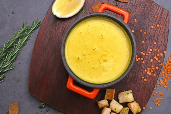 Delicious creamy lentil soup garnished with fresh herbs, served with croutons and a slice of lemon.
