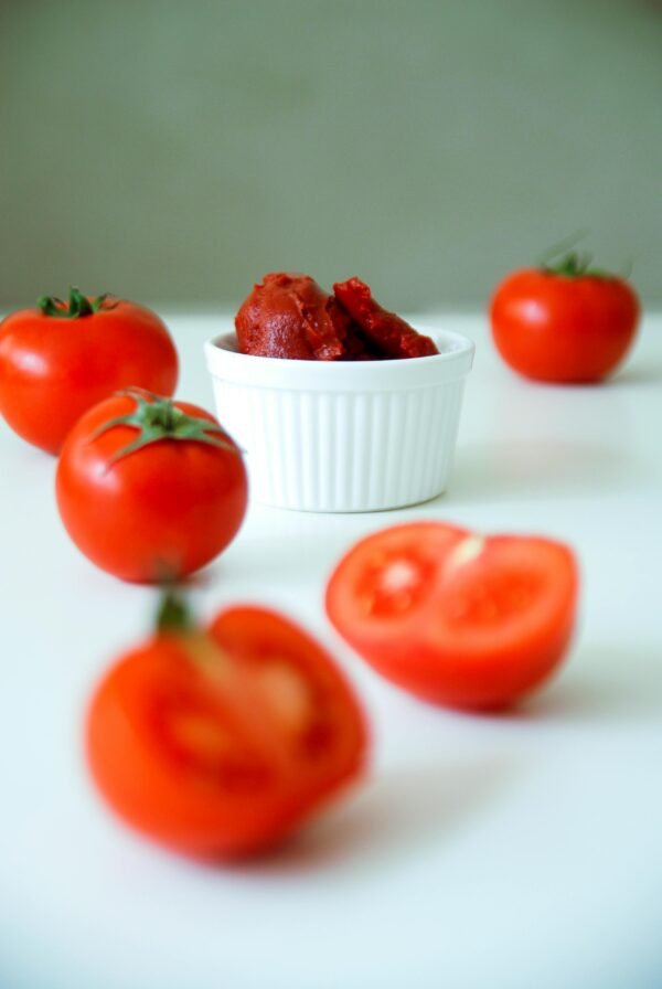 A vibrant arrangement of fresh tomatoes and tomato paste on a white background.