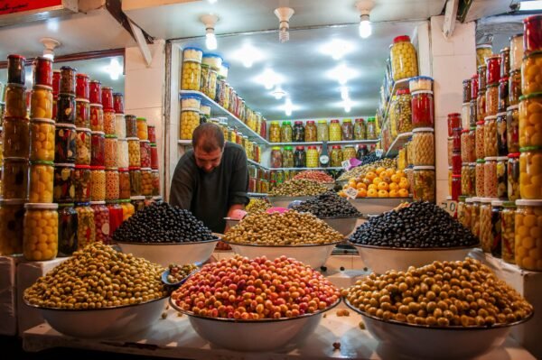 Young ethnic male selling assorted colorful fresh fruits and berries in local market