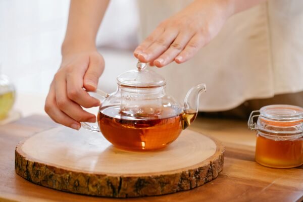 A close-up view of hands preparing herbal tea in a glass kettle. Warm and inviting.